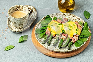 Delicious breakfast with eggs Benedict and green asparagus wrapped in grilled bacon and a cup of coffee. banner, menu, recipe