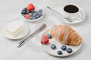 Delicious breakfast with fresh coffee, fresh croissants and berries on a white table. Selective focus