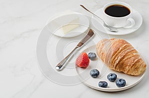 Delicious breakfast with fresh coffee, fresh croissants and berries on a white table. Selective focus and copy space