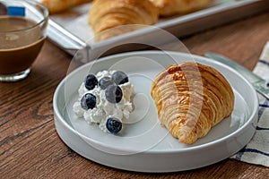 Delicious breakfast with fresh croissants with blueberry and cream.