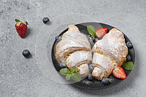 Delicious breakfast with fresh croissants and fresh ripe berries. Freshly baked croissants with strawberries and blueberries.