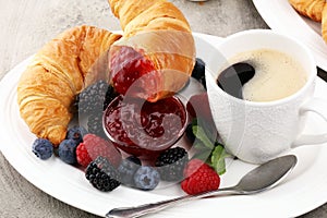 Delicious breakfast with fresh croissants and ripe berries and j