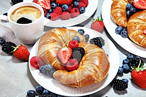 Delicious breakfast with fresh croissants and ripe berries on old marble background.