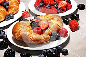 Delicious breakfast with fresh croissants and ripe berries on old marble background.