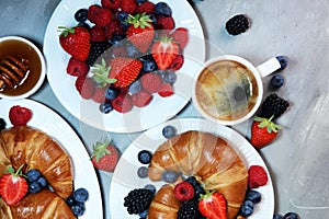 Delicious breakfast with fresh croissants and ripe berries on old marble background.