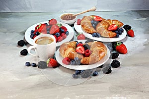 Delicious breakfast with fresh croissants and ripe berries on old marble background.