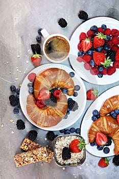 Delicious breakfast with fresh croissants and ripe berries on old marble background.