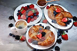 Delicious breakfast with fresh croissants and ripe berries on old marble background.