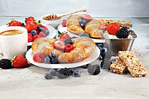 Delicious breakfast with fresh croissants and ripe berries on old marble background.
