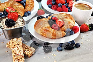 Delicious breakfast with fresh croissants and ripe berries on old marble background.