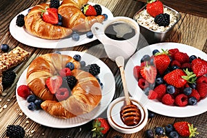 Delicious breakfast with fresh croissants and ripe berries on old marble background.