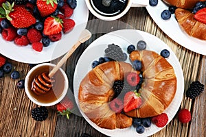 Delicious breakfast with fresh croissants and ripe berries on old marble background.