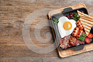 Delicious breakfast with heart shaped fried egg and  sausages on wooden table. Space for text