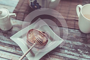 Delicious breakfast. Homemade Pancakes with honey and cup of tea on wooden rustic background table. Vintage style retro toned imag