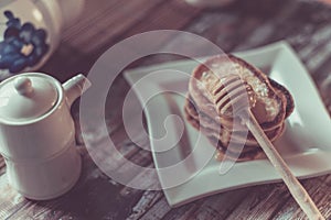 Delicious breakfast. Homemade Pancakes with honey and cup of tea on wooden rustic background table. Vintage style retro toned imag
