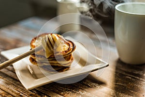 Delicious breakfast. Homemade Pancakes with honey and cup of tea on wooden rustic background table. Vintage style retro toned imag