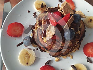 Delicious breakfast of pancakes with chocolate,  red berries, strawberries and blueberries