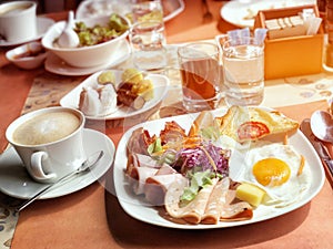 Delicious breakfast served with coffee, orange juice, egg, ham, salad, bacon rolls at the luxury hotel