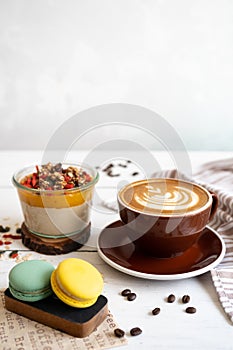 Delicious breakfast on the table. The cup of coffee, mango pudding and macarons at the white table