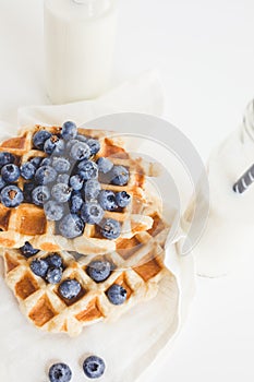 Breakfast of waffles with blueberries and two bottles of milk