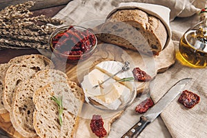 Delicious brie cheese Camembert with sun-dried tomatoes with olive oil and homemade bread. Traditional quick snack for home