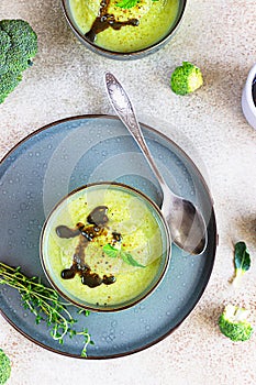 Delicious broccoli cream soup served with spicy oil and mint. Vegetarian dish. Top view. Light concrete background