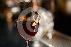 Delicious brown cocktail in the glass decorated with a dried leaf by a pin