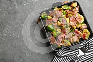 Delicious Brussels sprouts with bacon served on grey table, top view. Space for text