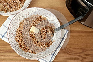 Delicious buckwheat and modern multi cooker on wooden table