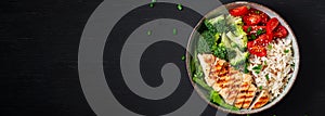 Delicious buddha bowl with grilled chicken, fresh vegetables and rice on a dark background. Top view, banner