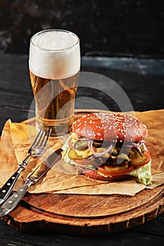 Delicious burger with beer and french fries on a wooden rustic table. Gamberger with salom onion and meat cutlet with a