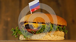 Delicious burger with small Russian flag on top of them with toothpicks. Yummy hamburger rotating.