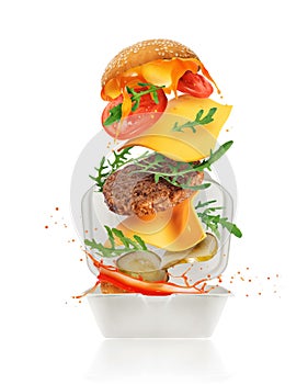 Delicious burger with various ingredients flies out of cardboard packaging isolated on a white background