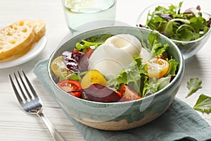 Delicious burrata salad with colorful cherry tomatoes and arugula served on white wooden table