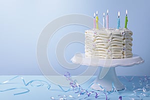 Delicious cake with burning candles and festive decor on light blue background. Space for text