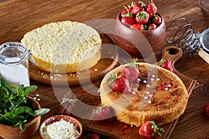 Delicious cake with fresh organic strawberries on cutting board over wooden background, close-up, selctive focus.