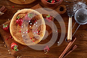 Delicious cake with fresh organic strawberries on cutting board over wooden background, close-up, selctive focus.