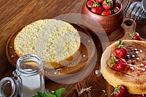 Delicious cake with fresh organic strawberries on cutting board over wooden background, close-up, selctive focus.