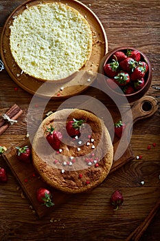 Delicious cake with fresh organic strawberries on cutting board over wooden background, close-up, selctive focus.