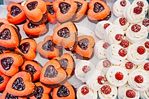 Delicious cakes in the form of hearts on a table for guests. Colorful sweets for special ocasion on a tray. Close-up.