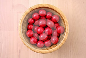 Delicious candies, nuts in red glaze lie in a bowl made of bamboo.