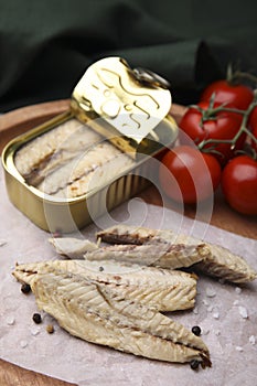 Delicious canned mackerel fillets and fresh tomatoes on wooden board, closeup