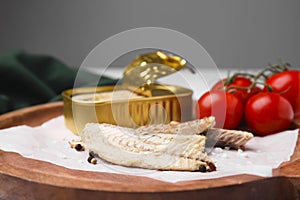Delicious canned mackerel fillets and fresh tomatoes on wooden plate, closeup