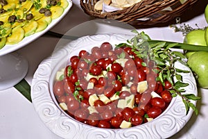 Delicious caprese salad with ripe cherry tomatoes and mini mozzarella cheese balls with fresh basil leaves. Italian healthy food