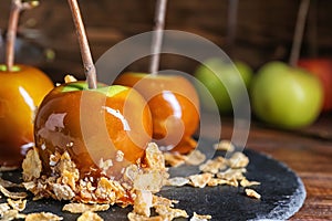 Delicious caramel apples with tree branches on slate plate