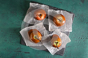 Delicious caramel apples with tree branches on slate plate