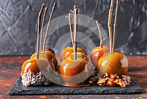 Delicious caramel apples with tree branches on slate plate