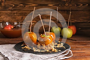 Delicious caramel apples with tree branches on slate plate