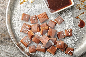 Delicious caramel candies, sauce and salt on plate