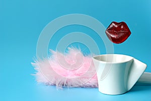 Delicious caramel lips over a coffee Cup next to pink feathers on a blue background